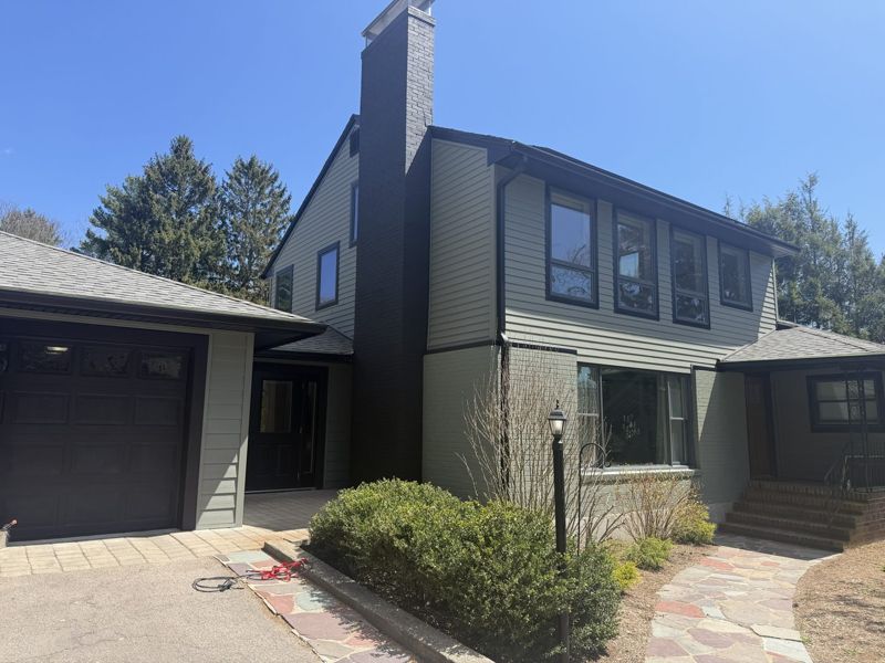 House exterior painted sage green with a dark painted brick chimney